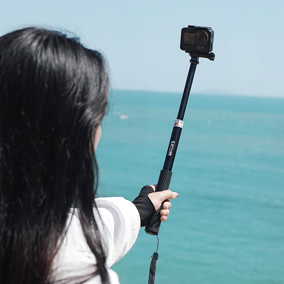 holding an Action Camera Selfie Stick over the ocean